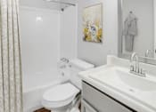 Thumbnail 8 of 9 - A white toilet sits next to a white sink in a bathroom.