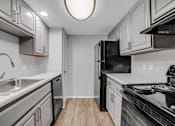 Thumbnail 1 of 9 - A kitchen with a black refrigerator and stove top oven.