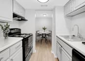 Thumbnail 2 of 9 - A kitchen with white cabinets and black appliances.