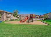 Thumbnail 5 of 5 - A playground with a red slide in the middle of a grassy area.