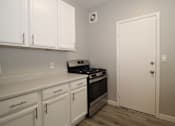 Thumbnail 11 of 59 - a kitchen with white cabinets and a stove and a door