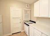 Thumbnail 26 of 59 - a kitchen with white cabinets and a stove and a door