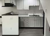 Thumbnail 6 of 17 - A kitchen with white cabinets and a black countertop.