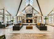 Thumbnail 1 of 28 - A large, open-concept living room with a stone fireplace and skylight.