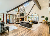 Thumbnail 2 of 28 - A modern living room with a stone fireplace and wooden floors.