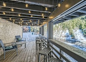 Thumbnail 7 of 28 - A wooden deck with a table and chairs overlooking a snowy landscape.