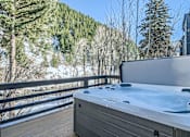Thumbnail 8 of 28 - A hot tub is on a deck with a snowy mountain in the background.