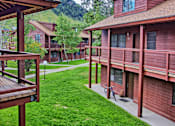 Thumbnail 1 of 17 - A mountain is behind a building with red siding.
