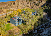 Thumbnail 22 of 28 - A building with a blue roof is situated in a valley with a river running through it.