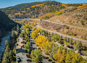 Thumbnail 23 of 28 - A river flows through a town with yellow trees.
