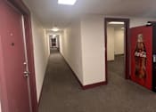 Thumbnail 3 of 6 - A long hallway with a Coca-Cola machine at the end.