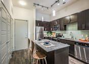 Thumbnail 16 of 19 - A kitchen with a granite countertop and stainless steel appliances.at Infinity on Yorktown, Dallas