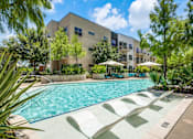 Thumbnail 13 of 19 - A swimming pool with sun loungers and a building in the background.at Infinity on Yorktown, Texas
