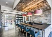 Thumbnail 2 of 19 - A modern kitchen with a wooden ceiling and a long island with chairs.at Infinity on Yorktown, Dallas, TX