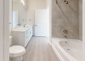 Thumbnail 9 of 17 - A white bathroom with a toilet, sink, and bathtub.