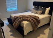 Thumbnail 22 of 25 - A bedroom with a bed covered in a brown blanket and pillows at Arden at Corinth, Corinth, TX 76210