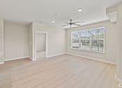 Thumbnail 13 of 19 - an empty living room with a large window and a ceiling fan at Creekside at Grand Prairie, Grand Prairie, 75052