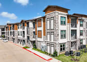 Thumbnail 4 of 19 - a row of apartment buildings on the side of a street at Creekside at Grand Prairie, Grand Prairie, Texas