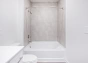 Thumbnail 12 of 17 - A white bathroom with a toilet, sink, and bathtub.