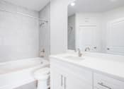 Thumbnail 11 of 17 - A white bathroom with a toilet, sink, and bathtub.