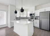 Thumbnail 5 of 17 - A modern kitchen with a white island and stainless steel appliances.