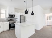 Thumbnail 6 of 17 - A modern kitchen with white cabinets and a central island.