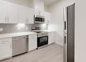 Thumbnail 14 of 17 - A modern kitchen with white cabinets and stainless steel appliances.