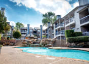Thumbnail 4 of 30 - a swimming pool with a waterfall in front of an apartment building at Infinity on the Mark, Dallas, TX, 75243