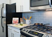 Thumbnail 4 of 17 - A modern kitchen with a stove, refrigerator, and microwave. at The Ellington Apartments, New York, NY, 10019