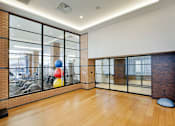 Thumbnail 19 of 24 - A room with a wooden floor and a glass wall with a view of a gym.