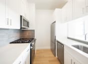 Thumbnail 3 of 24 - A kitchen with white cabinets and a stove top oven.