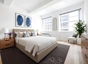 Thumbnail 4 of 24 - A bedroom with a large bed and two blue framed pictures on the wall.
