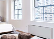 Thumbnail 13 of 24 - A bedroom with a large bed and a large window overlooking a cityscape.at 21 West, New York, NY