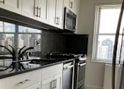 Thumbnail 10 of 12 - A kitchen with black countertops and white cabinets at The Caldwell Apartments, New York, New York