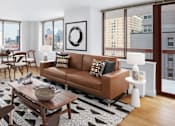 Thumbnail 11 of 17 - A living room with a brown couch and a coffee table at The Ellington Apartments, New York, 10019
