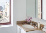 Thumbnail 8 of 17 - A bathroom with a large window overlooking a cityscape at The Ellington Apartments, New York, NY