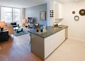 Thumbnail 7 of 15 - A modern kitchen with a refrigerator on the right side at The Maximilian Apartments, Long Island City