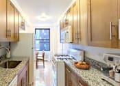 Thumbnail 3 of 18 - A kitchen with wooden cabinets and granite countertops.at Sutton Collection, New York, NY