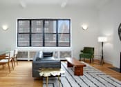 Thumbnail 8 of 18 - A living room with a fireplace and a large window.at Sutton Collection, New York, NY 10022