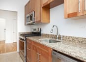 Thumbnail 11 of 18 - A kitchen with granite countertops and wooden cabinets.at Sutton Collection, New York