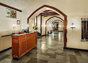 Thumbnail 17 of 18 - A hallway with a wooden reception desk and a vase of flowers on top. at Sutton Collection Apartments, New York