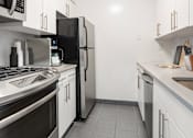 Thumbnail 9 of 17 - A modern kitchen with stainless steel appliances and white cabinets. at The Ellington Apartments, New York