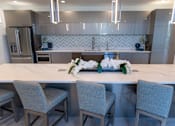Thumbnail 16 of 22 - A modern kitchen with a marble countertop and grey chairs.