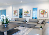 Thumbnail 20 of 22 - A modern living room with a grey sofa, a coffee table, and three framed pictures on the wall.