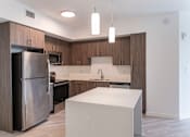 Thumbnail 9 of 22 - A modern kitchen with a white island and stainless steel appliances.