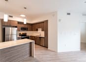 Thumbnail 11 of 22 - A modern kitchen with a refrigerator, microwave, oven, and sink.
