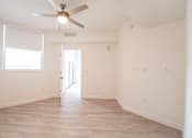 Thumbnail 8 of 22 - A room with a ceiling fan and a door leading to another room.