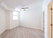 Thumbnail 10 of 22 - A room with a ceiling fan and light, hardwood floors, and a window.