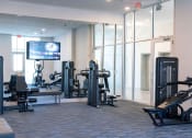 Thumbnail 23 of 36 - a gym with cardio equipment and a tv in a room with glass walls