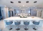 Thumbnail 27 of 41 - a large kitchen with a white counter top and blue chairs